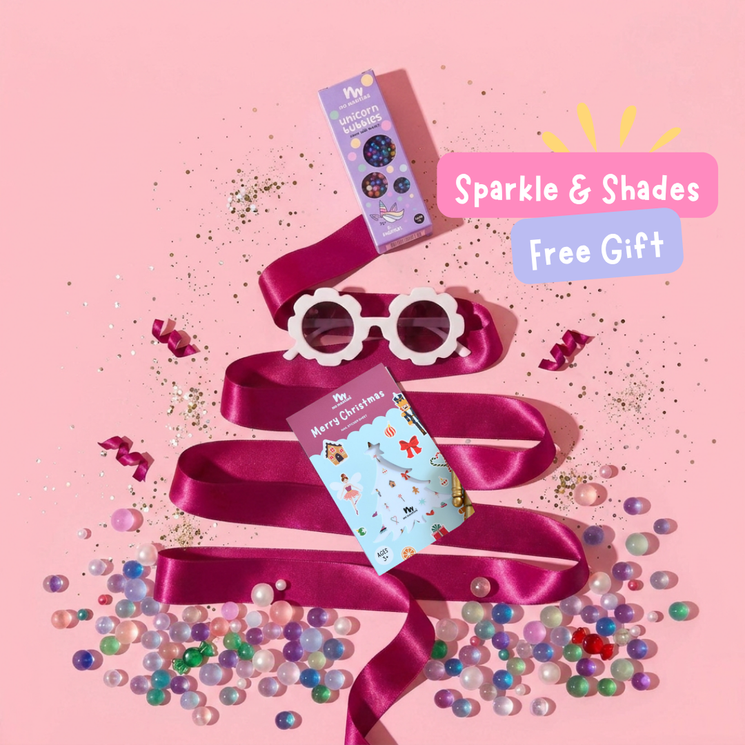 Purple sating ribbon in the shape of a Christmas tree with No Nasties Kids Unicorn Bubbles , Christmas nail stickers and white flower shaped sunglasses on a pink background