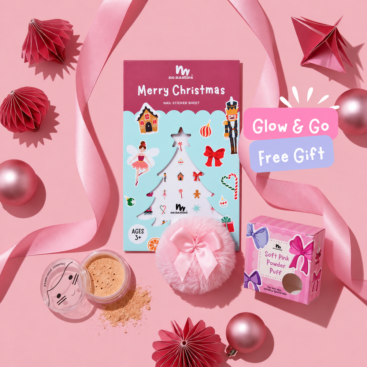 Christmas nail stickers, pink powder puff, gold shimmer powder on pink background with satin ribbons and Christmas baubles