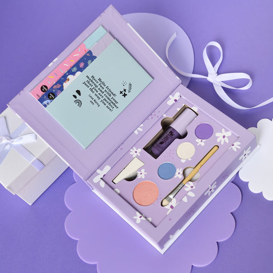 gift set for girls in purple with makeup kit nai stickers, water beads, makeup brush set, lip glosss and little girl holding a nancy makeup box on pastel purple and blue background