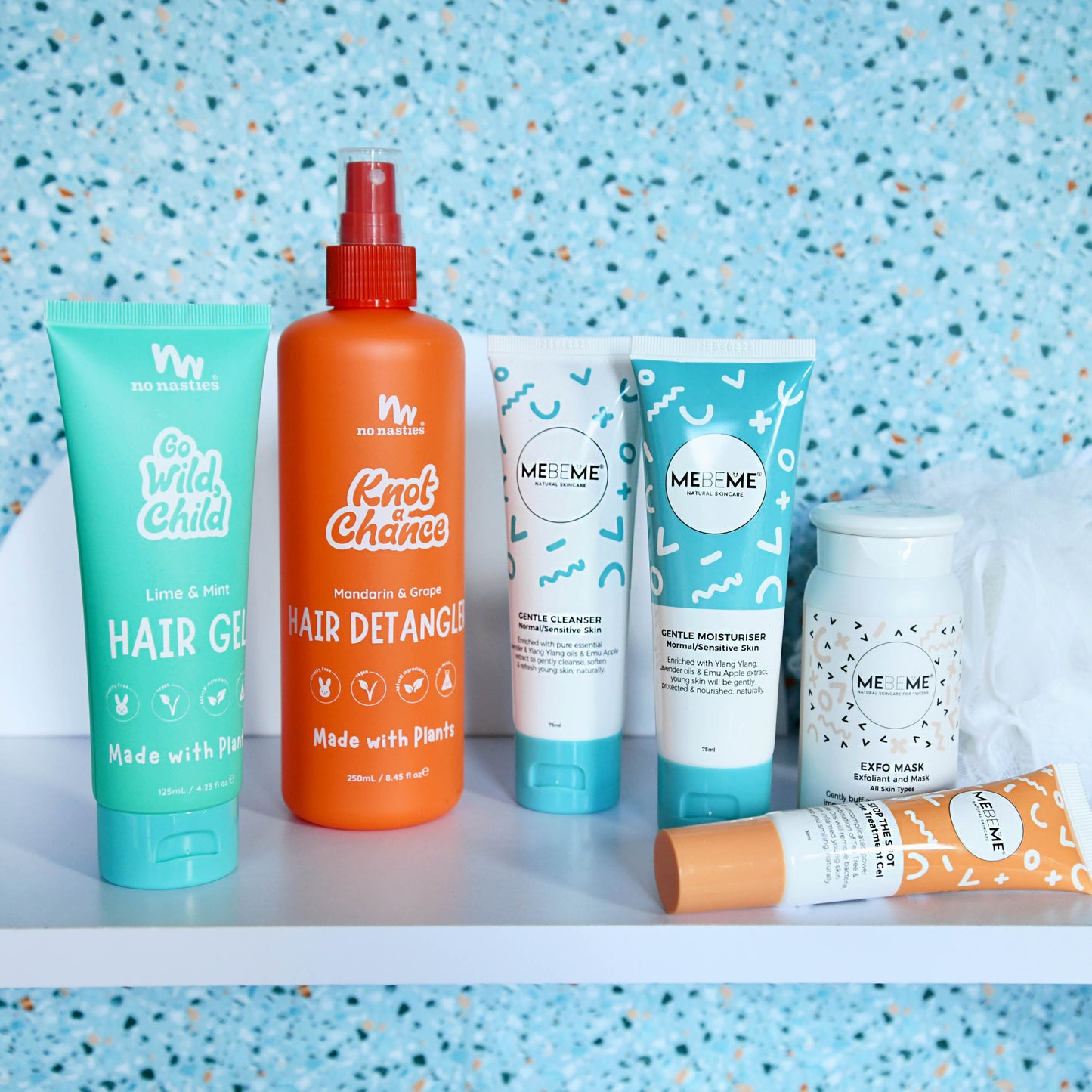 Collection of ME ME hair care products on a shelf with a blue speckled background