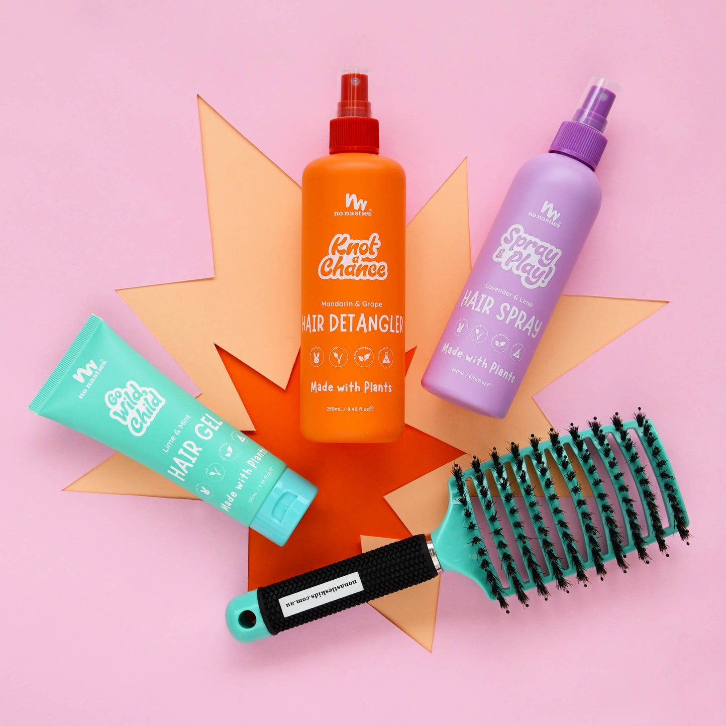 Set of hair care products including a detangler, spray, gel, and brush on a pink background