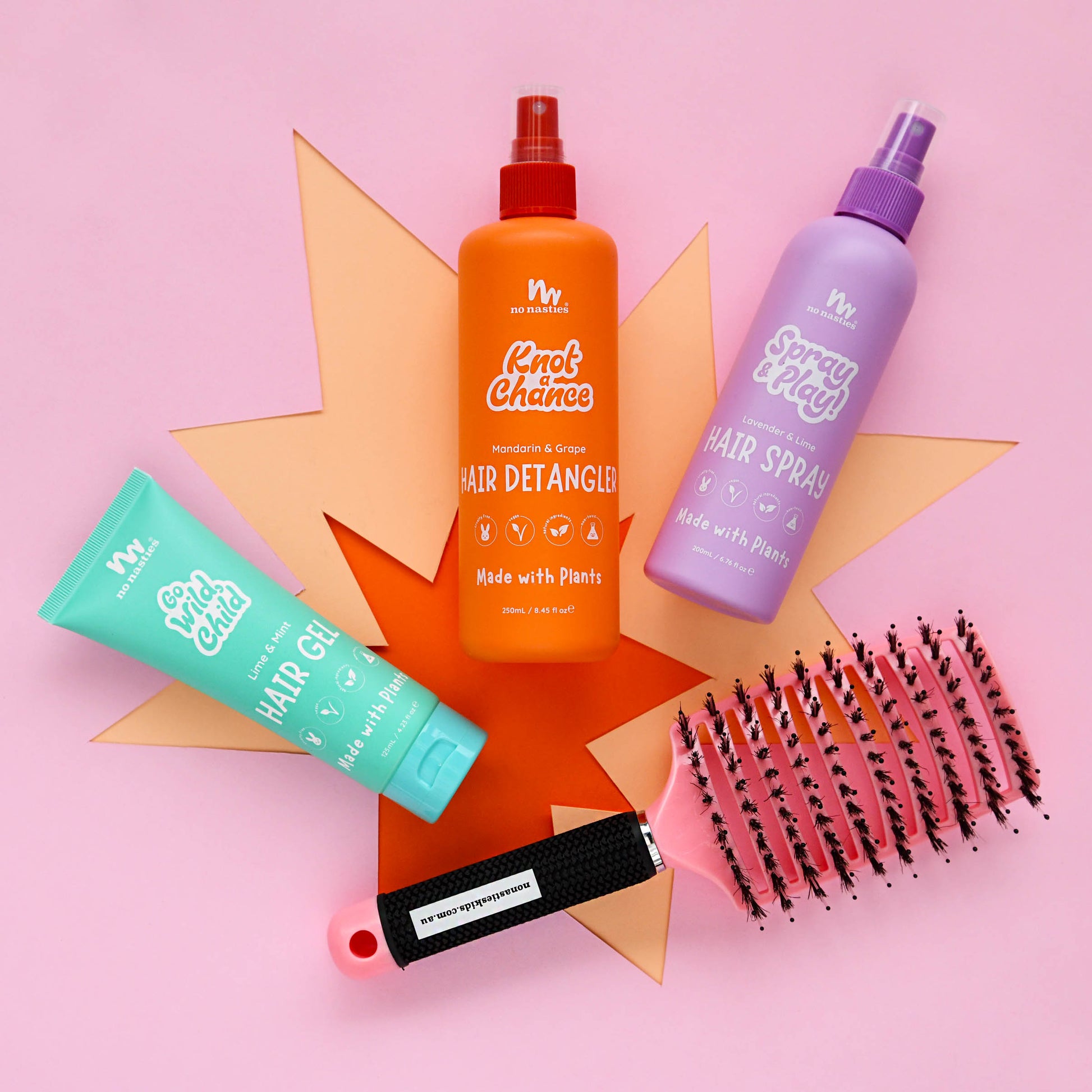 Set of hair care products including a detangler, spray, gel, and comb on a pink background