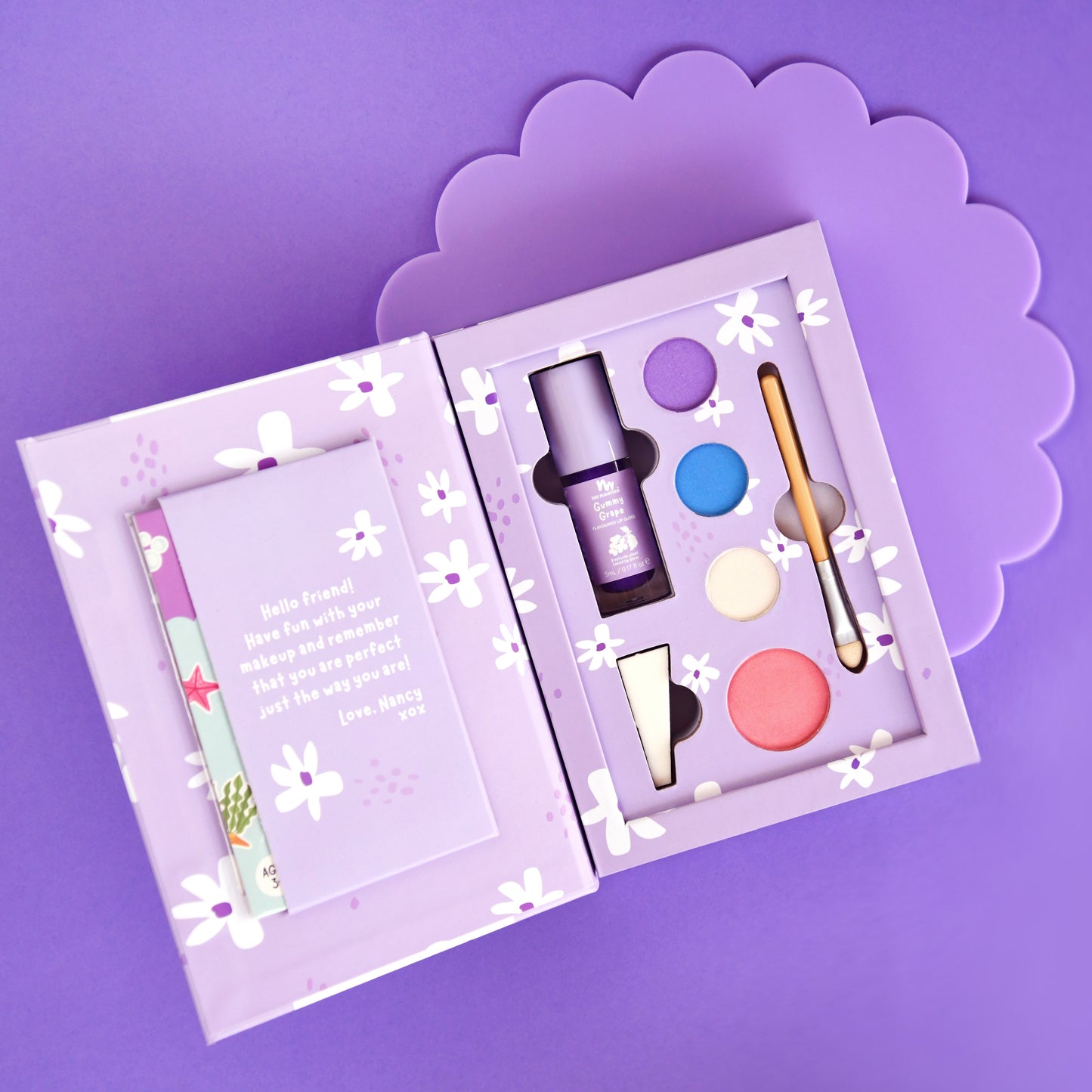 Inside view of Nancy purple deluxe kids makeup set showing pressed powders and applicators