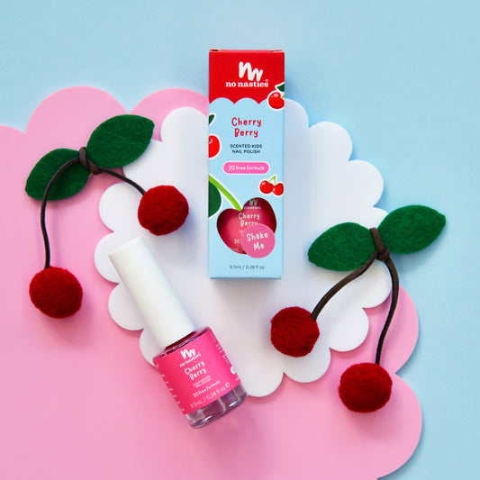 Cherry-themed nail polish with packaging and hair ties on a colorful background