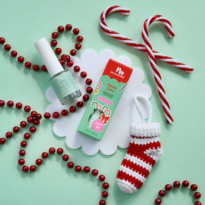 Christmas-themed nail polish with candy canes, beads, and a small stocking on a light green background.