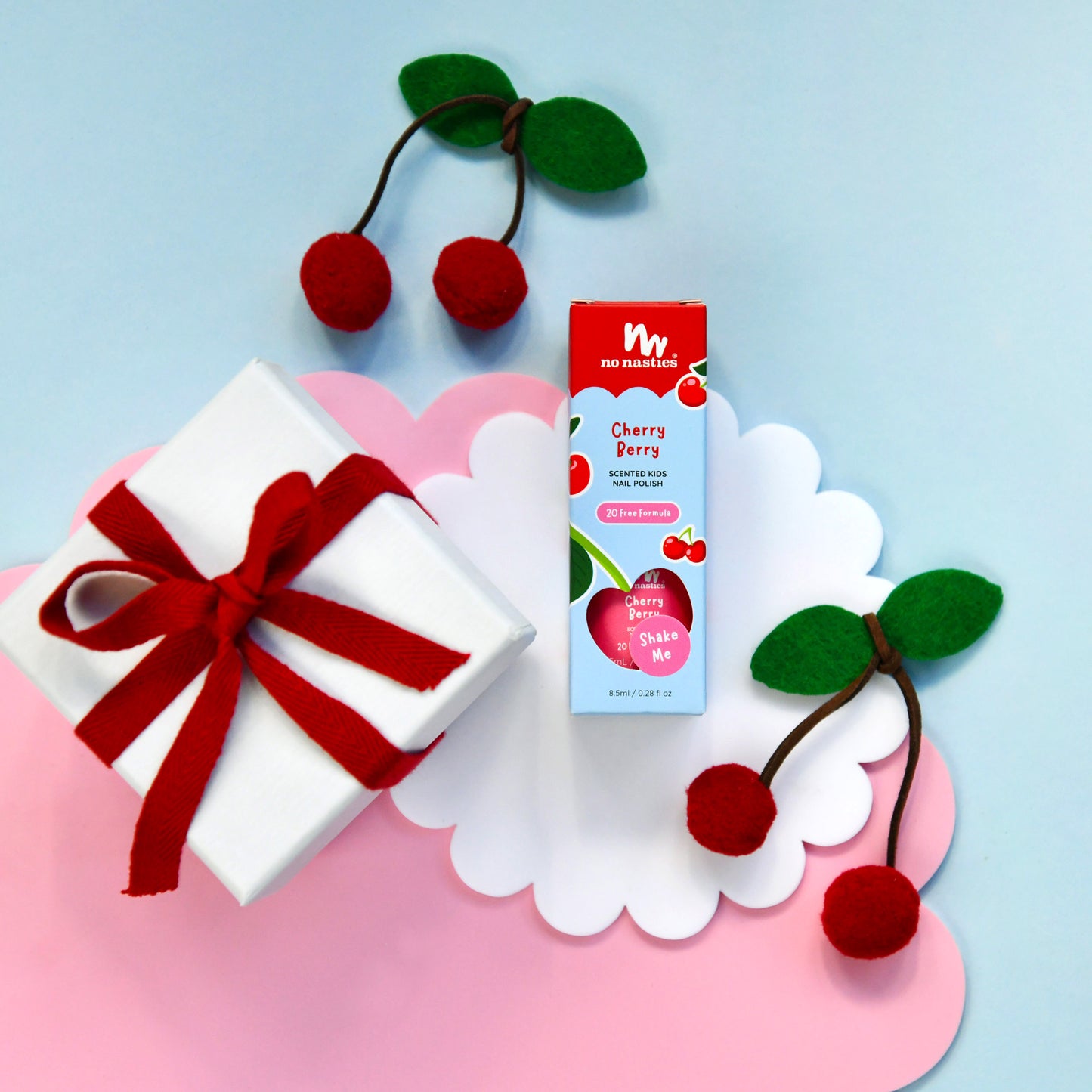 Gift box with red ribbon, cherry-themed product, and decorative cherries on a light blue background