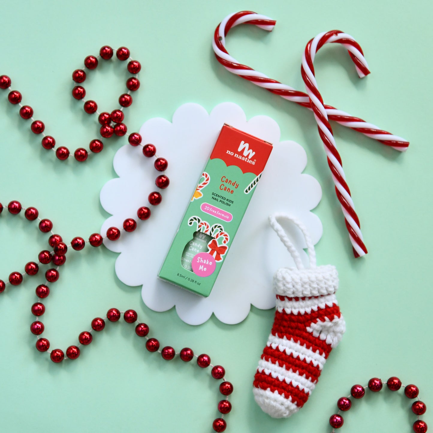 Candy cane, red and white striped stocking, and red bead necklace on a light green background