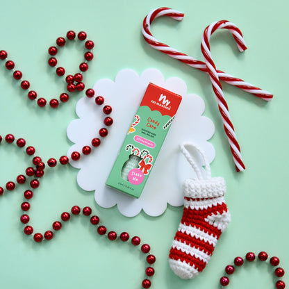 Candy cane, red and white striped stocking, and red bead necklace on a light green background