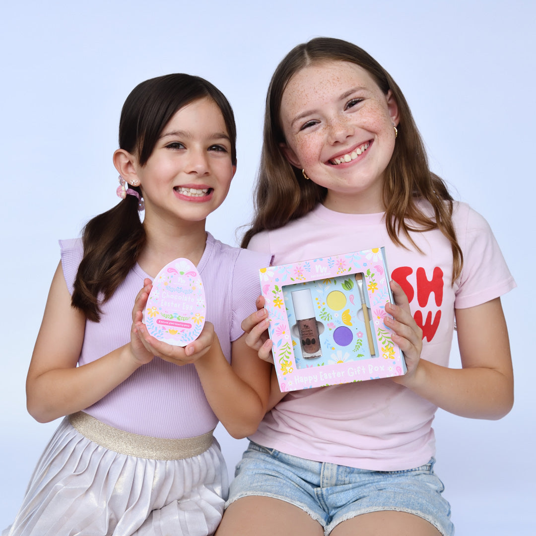 Two young girls holding decorative items against a light blue background