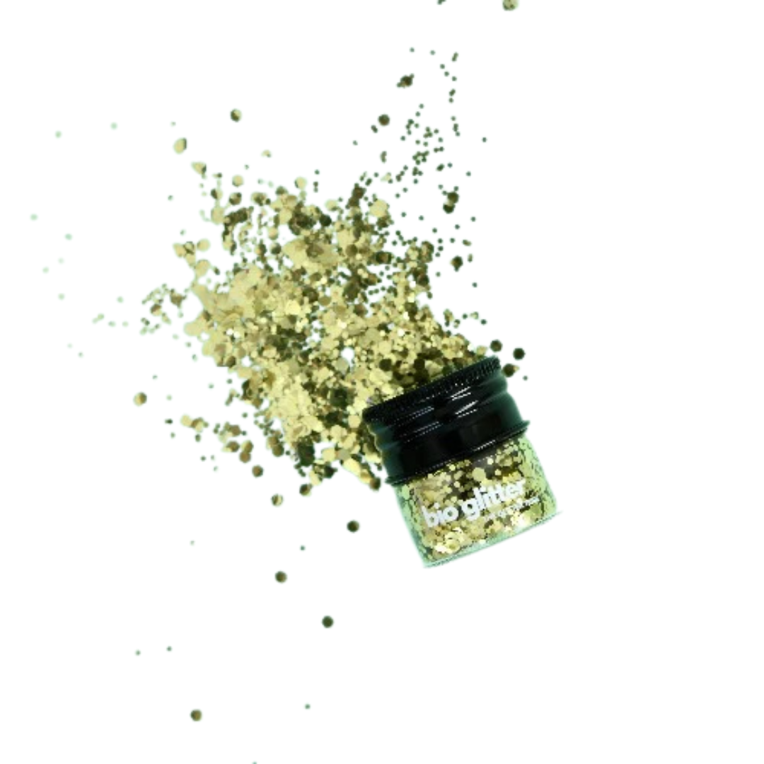 Gold biodegradable glitter spilling out of a container on a white background
