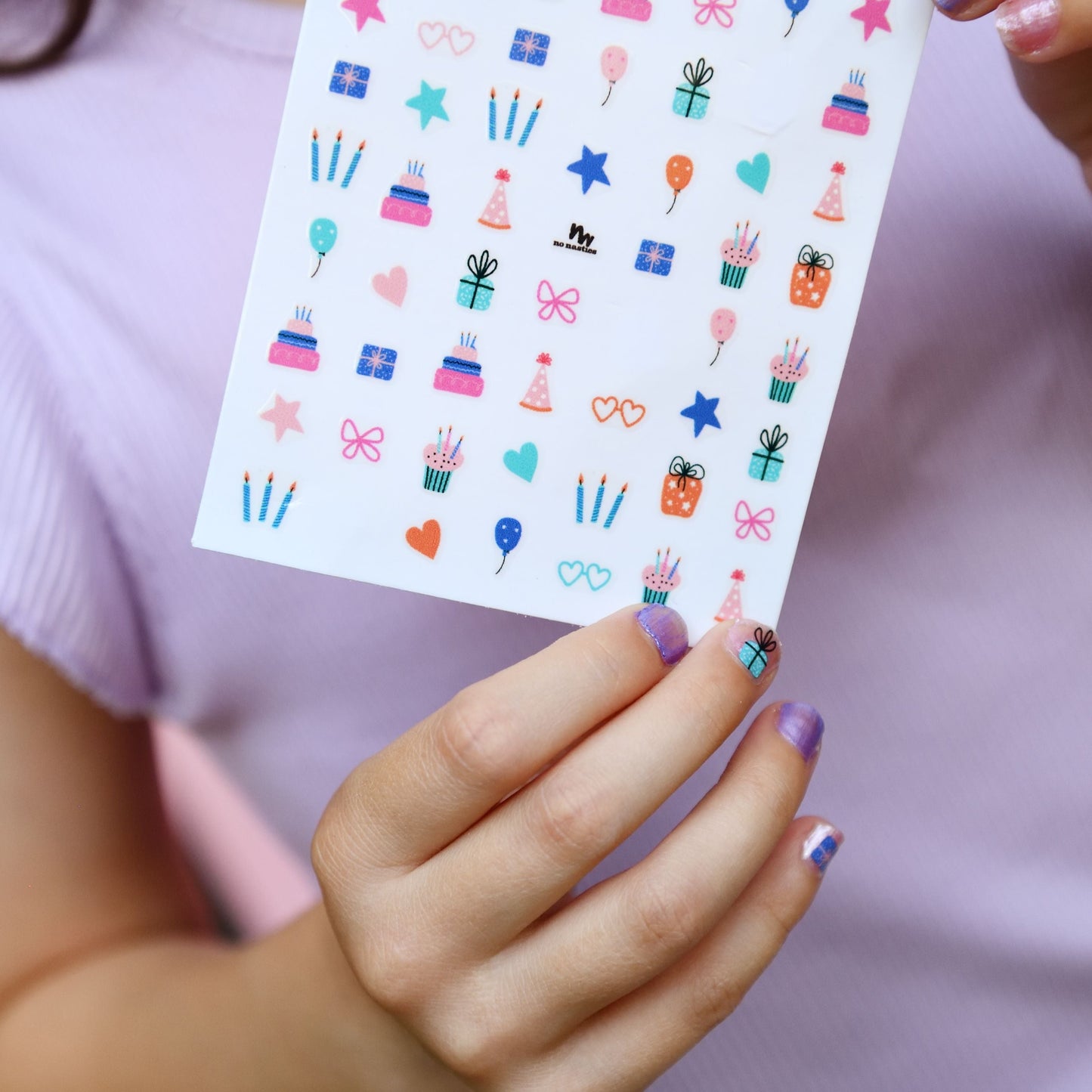 Person holding a sheet of colorful stickers with various designs.