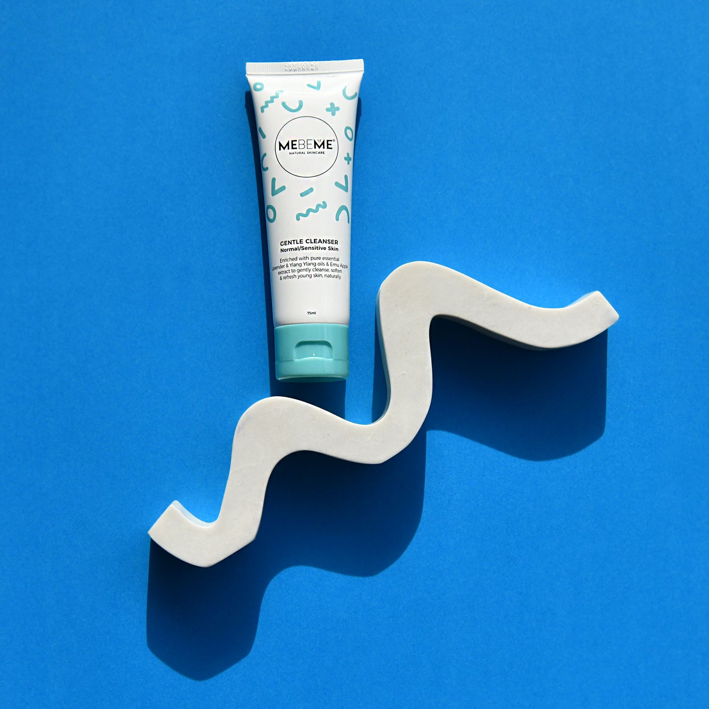 Tube of ME&ME Gentle Cleanser on a wavy white stand against a blue background