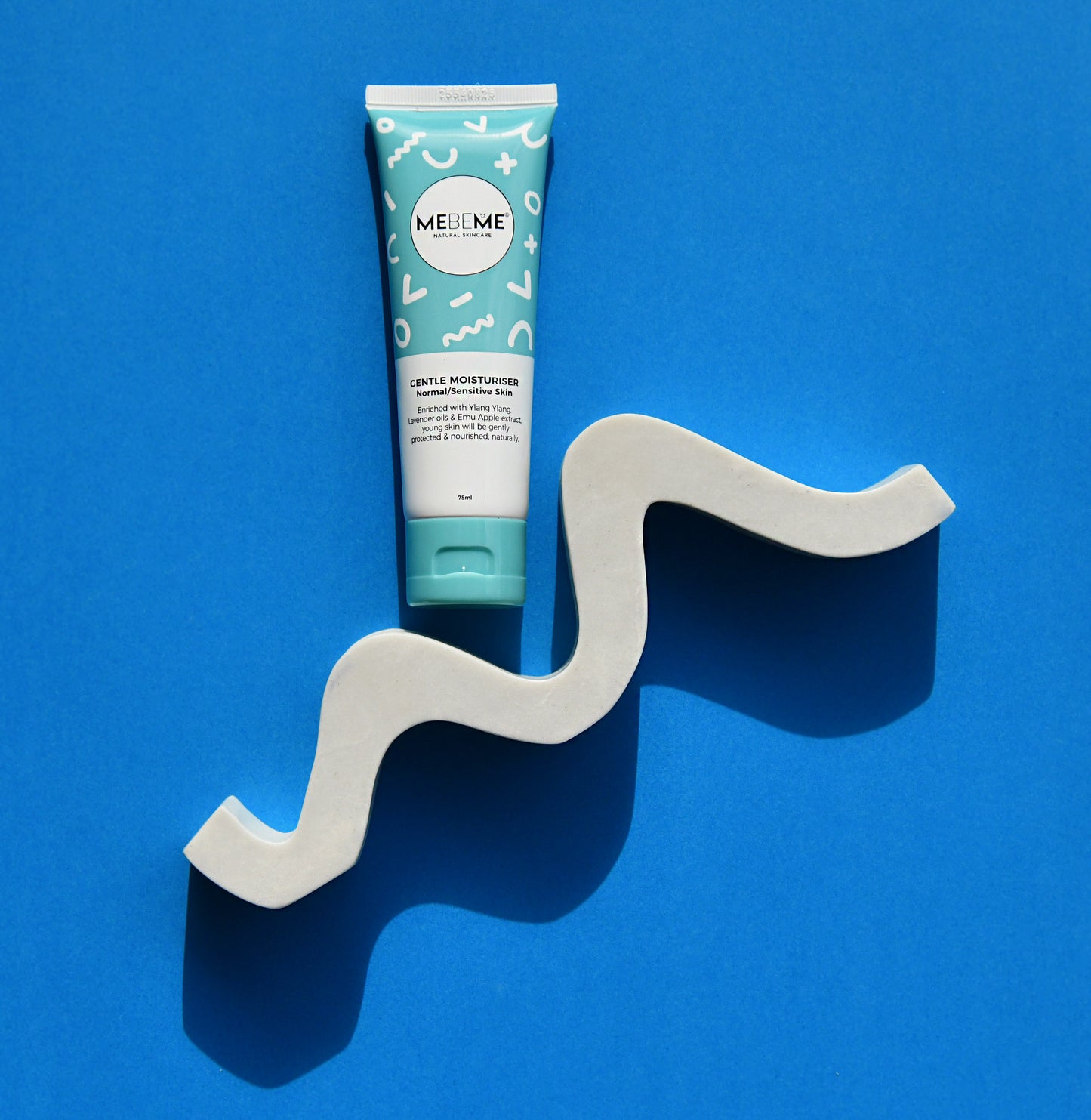 Tube of ME&ME product on a wavy gray stand against a blue background
