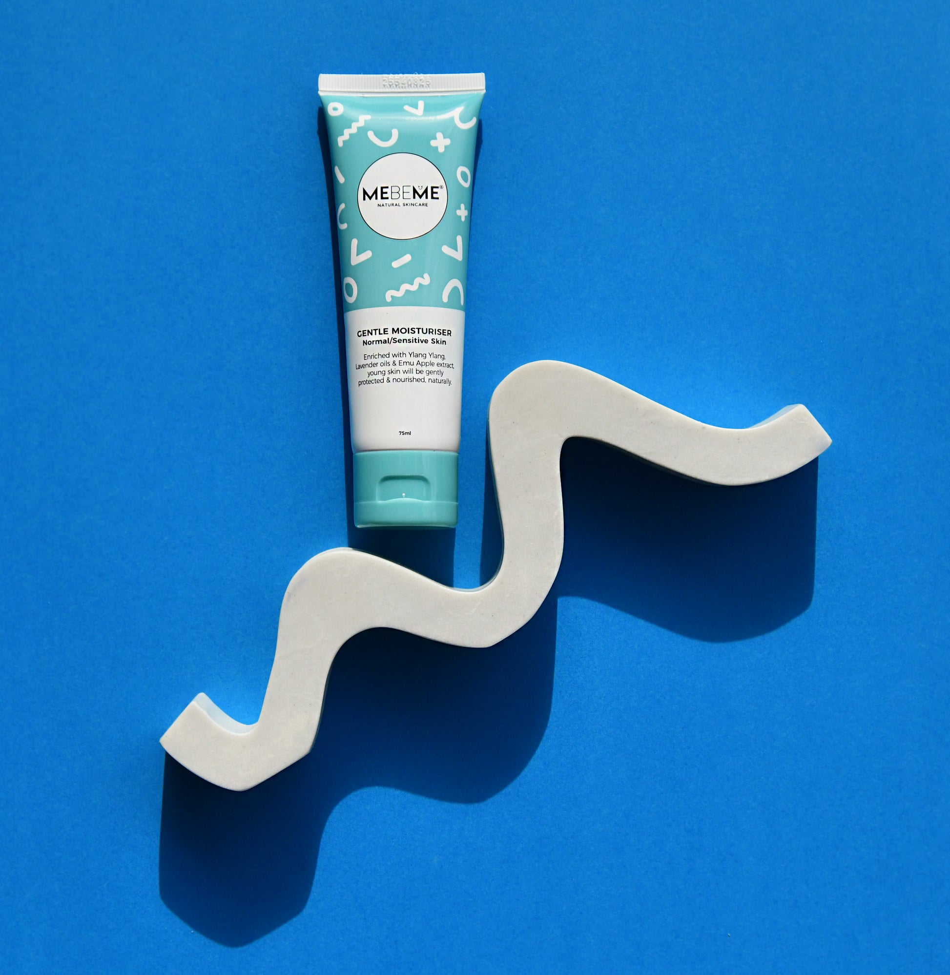 Tube of ME&ME product on a wavy gray stand against a blue background