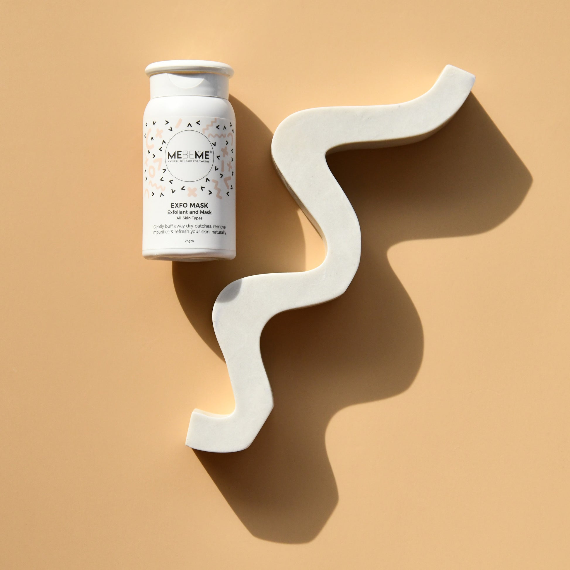 White skincare product container with decorative white wall art on a beige background