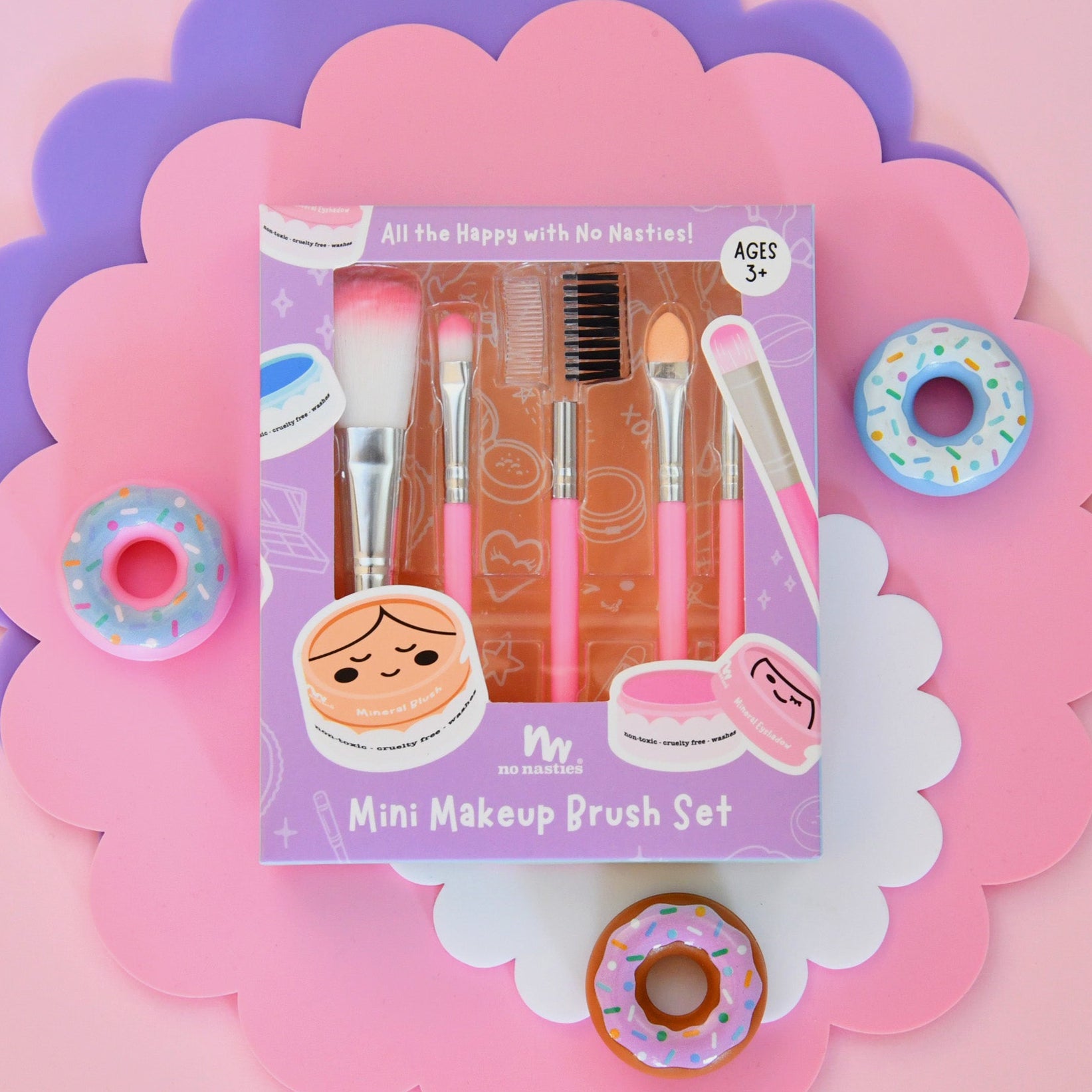 Mini makeup brush set packaging with decorative elements on a pink background
