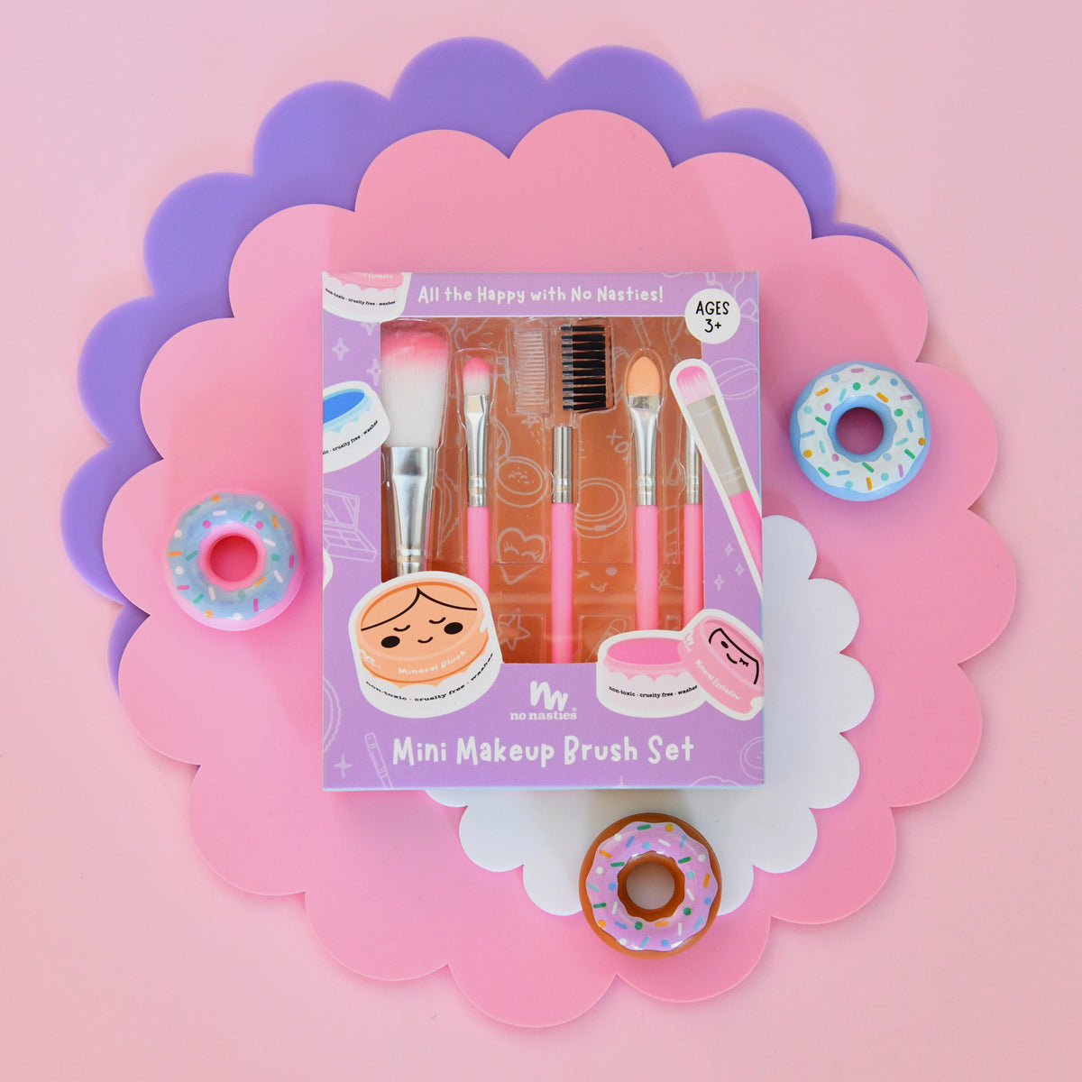 Mini makeup brush set packaging with decorative elements on a pink background