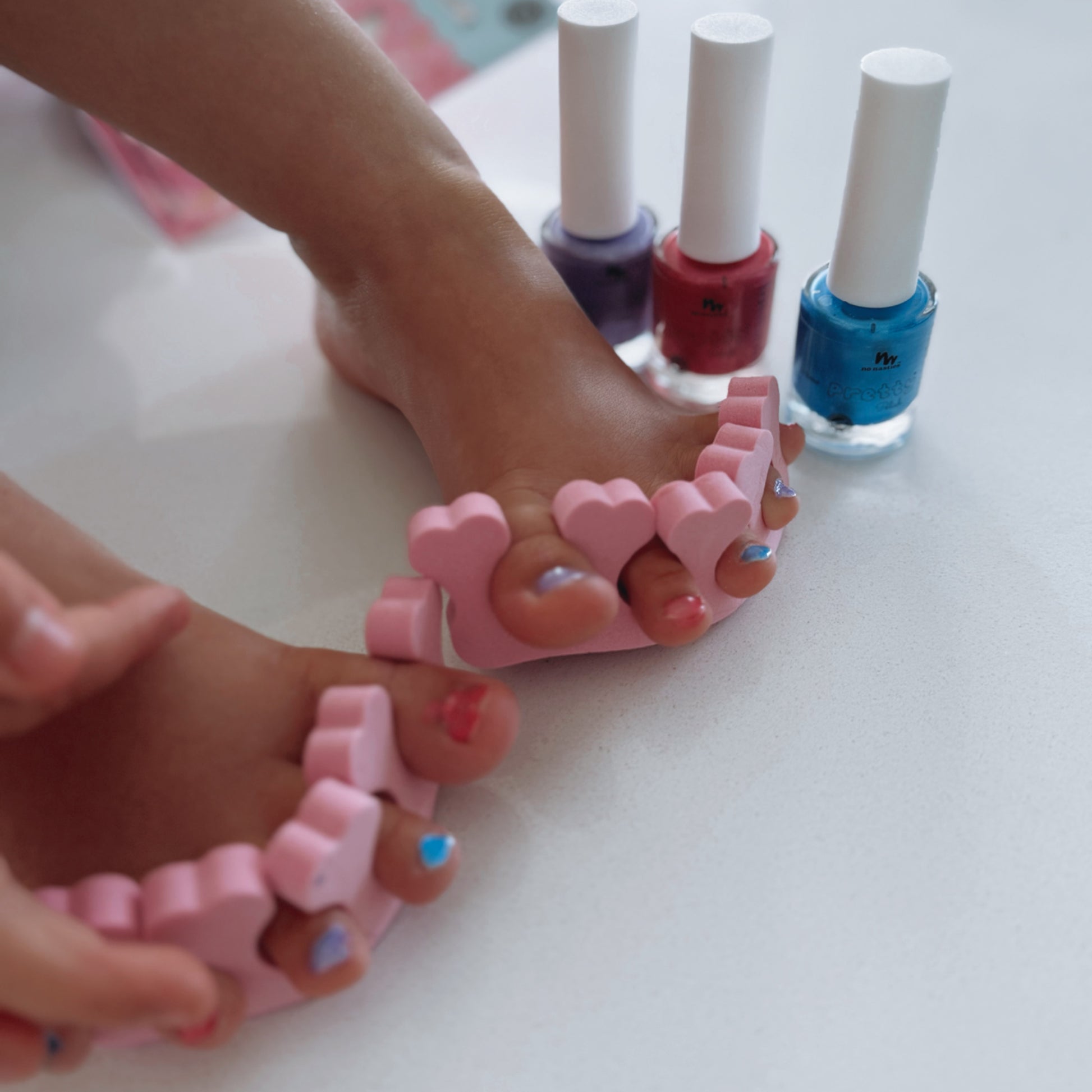kids toes with toe seperators and nails painted in different colours.