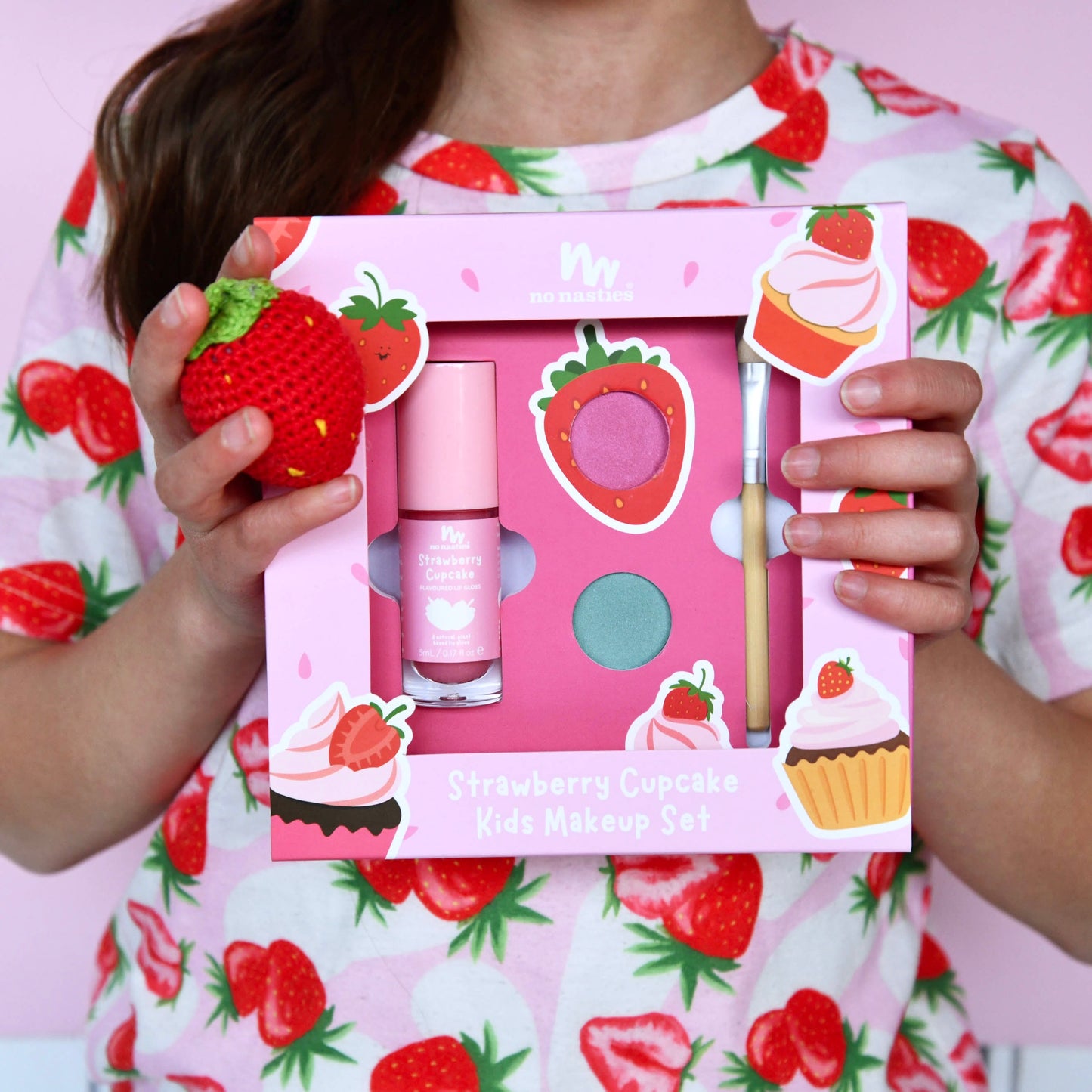 Strawberry-themed kids makeup set held by a person in a strawberry-patterned shirt.