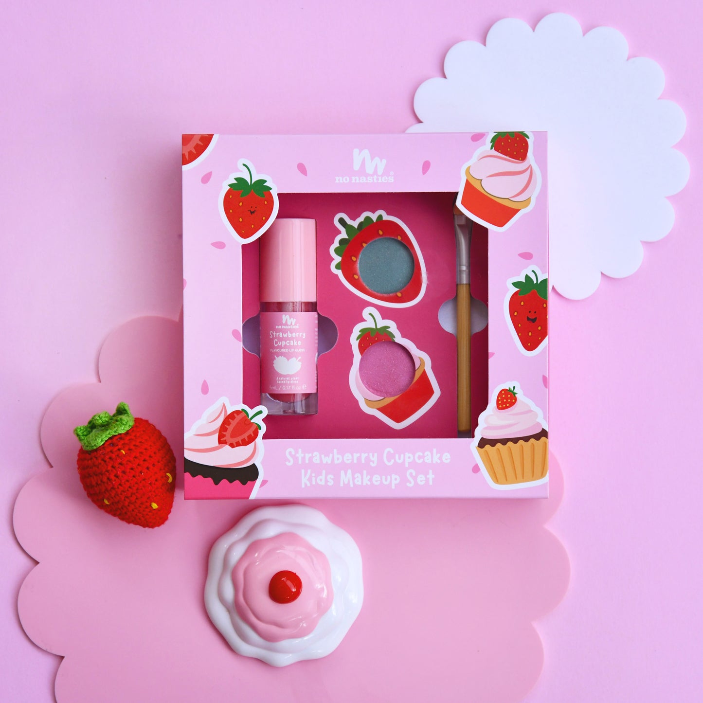 Strawberry-themed kids makeup set with packaging on a pink background