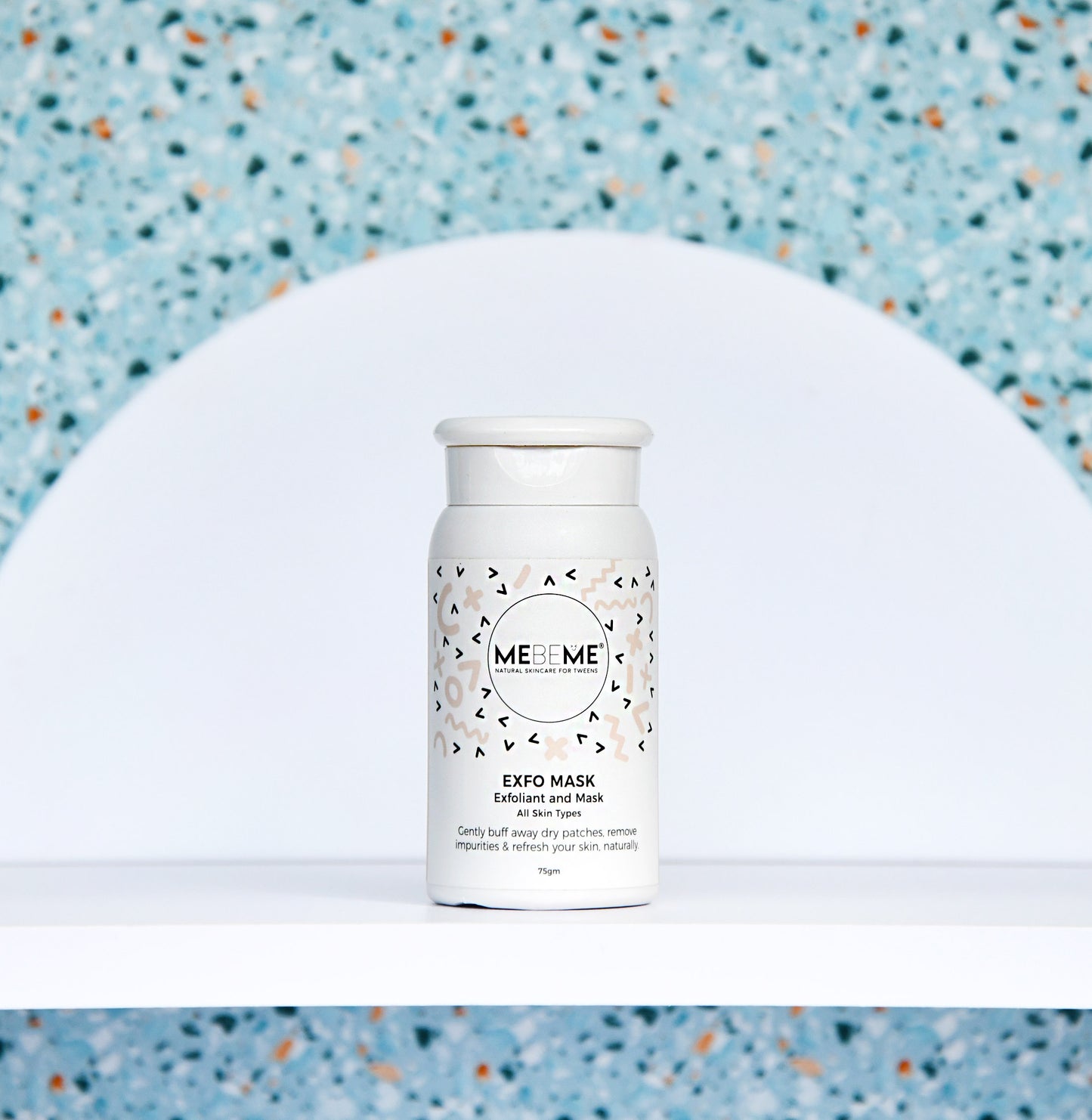 White skincare product bottle with a patterned label on a textured blue background