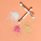 Applicator brush on orange background with mica powder