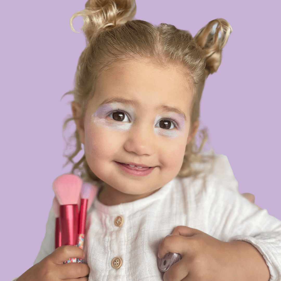 girl-with-shimmery-eyeshadow-holding-pink-twinkle-mkaeup-brushes